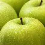 Närbild av gröna äpplen med regndroppar
